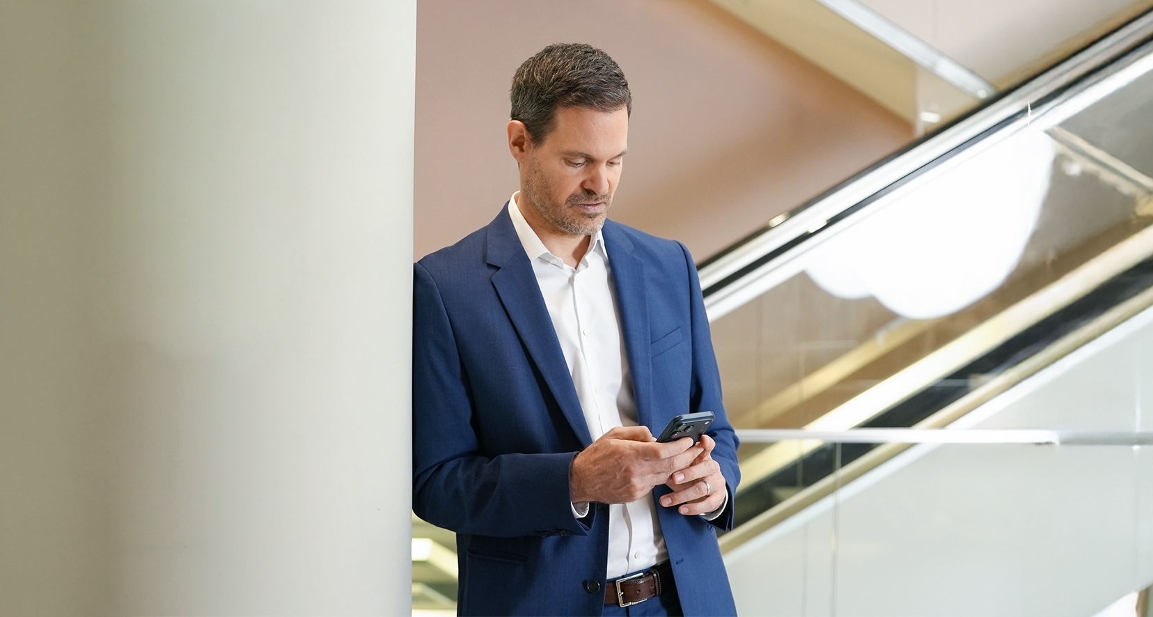 Benjamin Otto an einer Säule gelehnt mit Handy in der Hand