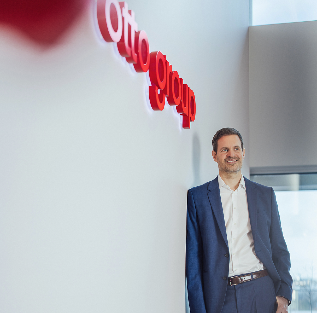 Benjamin Otto an Wand gelehnt mit Otto Group Schriftzug
